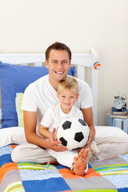 Portrait of a little boy and his father playing with a soccer ba clipart