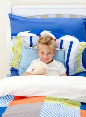 Adorable little boy lying in bed clipart