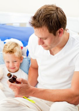 Attractive father giving cough syrup to his sick son clipart