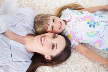 Jolly mother and her daughter lying on the floor clipart