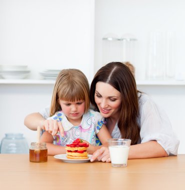 Loving little girl and her mother having breakfast clipart