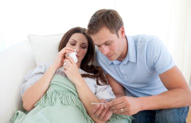 Attentive husband taking his wife's temperature clipart