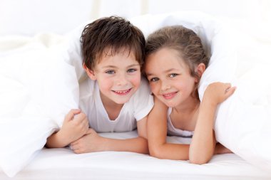 Brother and sister playing on parent's bed clipart