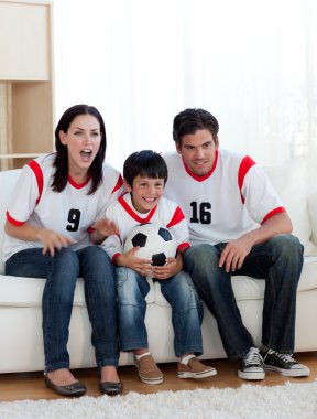 Parents and their son watching a football match clipart