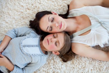 Mother and her daughter slepping on the floor clipart