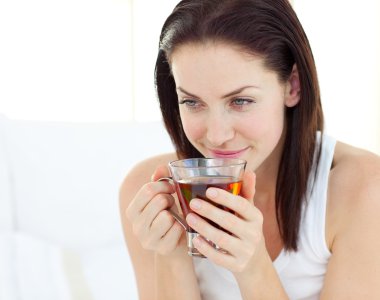 Delighted woman drinking a tea clipart