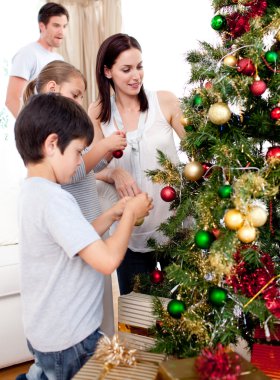 Happy children and parents decorating a Christmas tree clipart