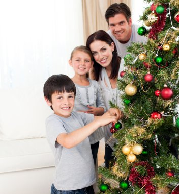 Smiling family decorating a Christmas tree clipart