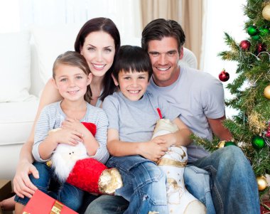 Portrait of a smiling family at Christmas time holding lots of p clipart