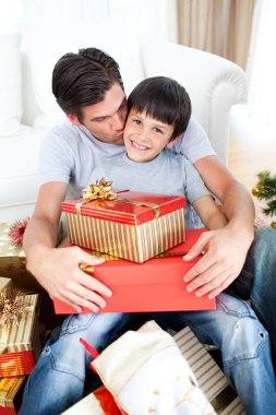 Father kissing his son after giving him a Christmas gift clipart