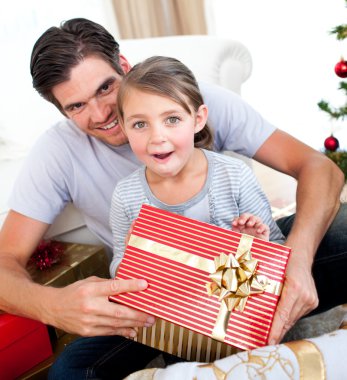 Surprised little girl opening a Christmas present with her fathe clipart