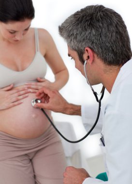 Beautiful pregnant woman examined by her gynecologist clipart