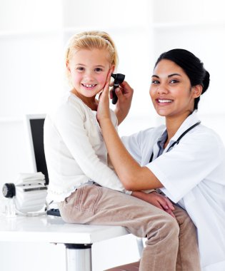 Smiling female doctor checking her patient's ears clipart