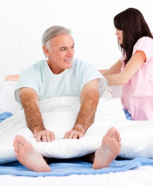 Attentive nurse fixing her patient's bed clipart