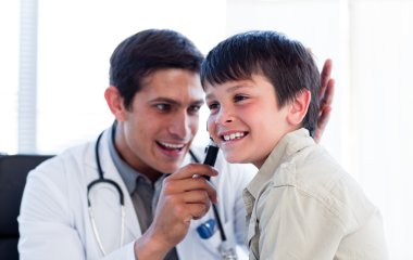 Smiling doctor examining little boy's ears clipart