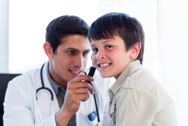 Concentrated doctor examining little boy's ears clipart