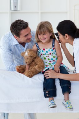 Female doctor checking smiling girl's ears clipart