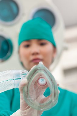 Confident doctor applying gas mask to a patient clipart