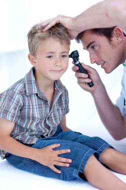 Doctor examining a patient' s ears with a otoscope clipart