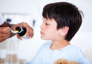 Cute sick little boy taking medicine clipart