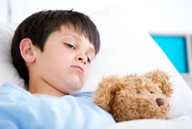 Portrait of a sick boy lying in a hospital bed clipart