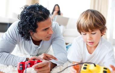 Father and his son playing video games lying on the floor clipart