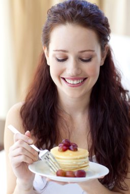 Smiling woman eating a sweet dessert clipart
