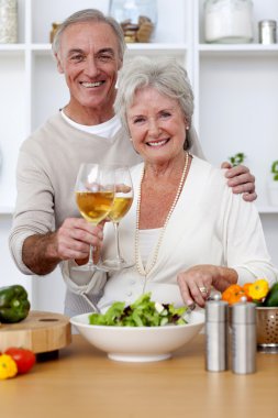 Happy senior couple eating a salad in the kitchen clipart