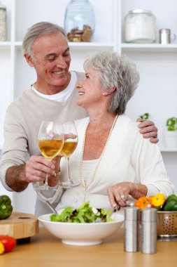 Senior couple in love eating a salad in the kitchen clipart