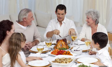 Father serving turkey to his family in a dinner clipart