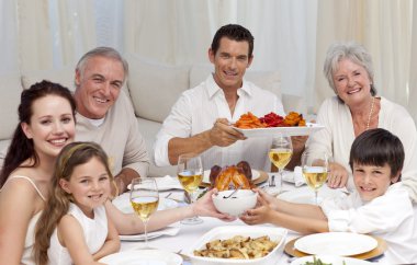 Grandparents, parents and children having a family dinner clipart