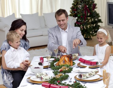 Father cutting a turkey in Christmas dinner clipart