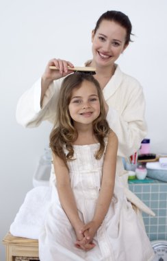 Mother doing her daughter's hair clipart