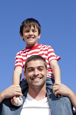 Father giving his son piggyback ride outdoors clipart