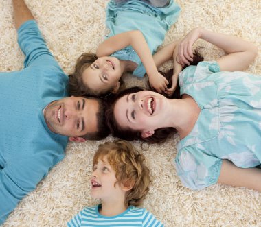 Smiling family on floor with heads together clipart