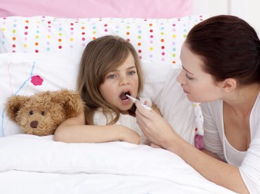 Mother taking her daughter's temperature with a thermometer clipart