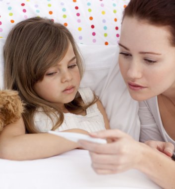 Portrait of mother taking her daughter's temperature clipart