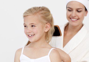 Young mother doing daughter's hair clipart