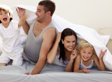 Family having fun in parent's bed clipart