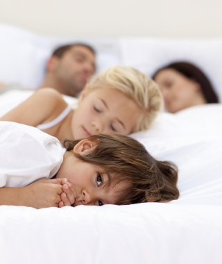 Little boy relaxing with his parents and sister sleeping clipart