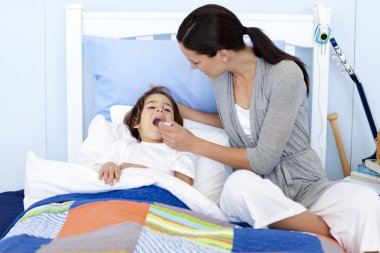 Mother taking her son's temperature with a thermometer clipart