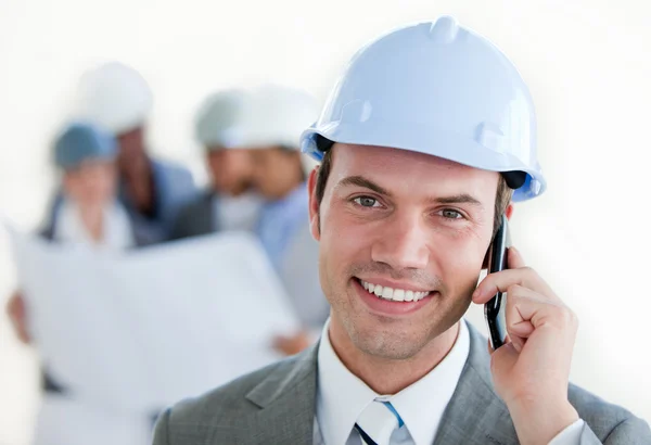 Arhitect sorridente com um chapéu duro no telefone — Fotografia de Stock