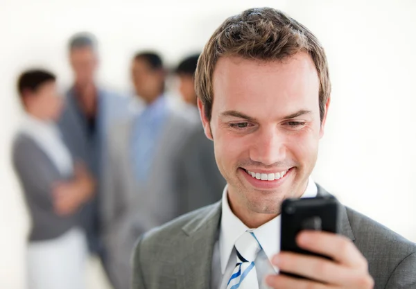 Empresário atraente enviando um texto na frente de sua equipe — Fotografia de Stock