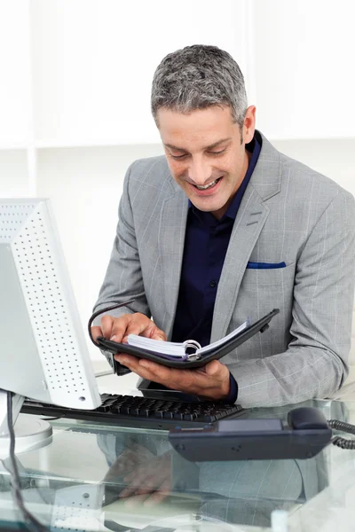 Smiling businessman consulting his agenda — Stock Photo, Image