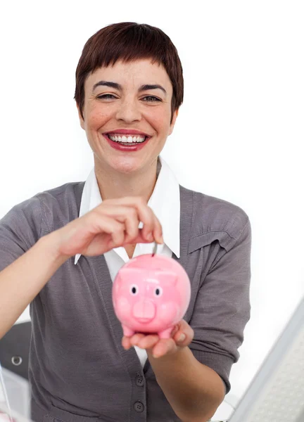 Attraktiva affärskvinna spara pengar i en piggybank — Stockfoto