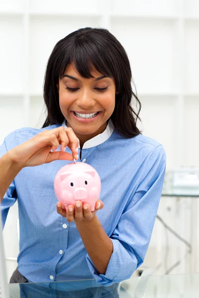Begeisterte ethnische Geschäftsfrau, die Geld in einem Sparschwein anspart — Stockfoto