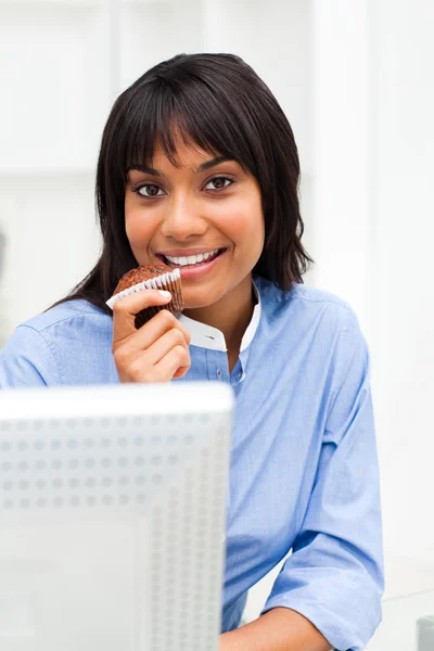 Glimlachende zakenvrouw eten een muffin — Stockfoto