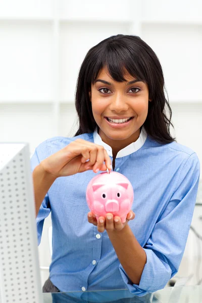 Påstridig etniska affärskvinna spara pengar i en piggybank — Stockfoto