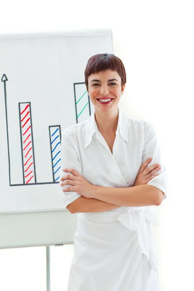 Mujer de negocios sonriente con los brazos cruzados delante de una tabla — Foto de Stock