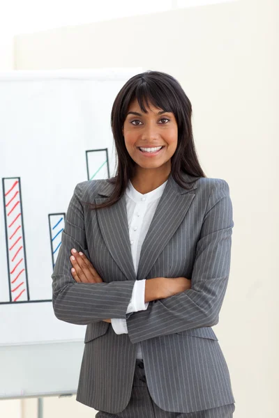 Ethnic businesswoman with folded arms in front of a board — Stock Photo, Image